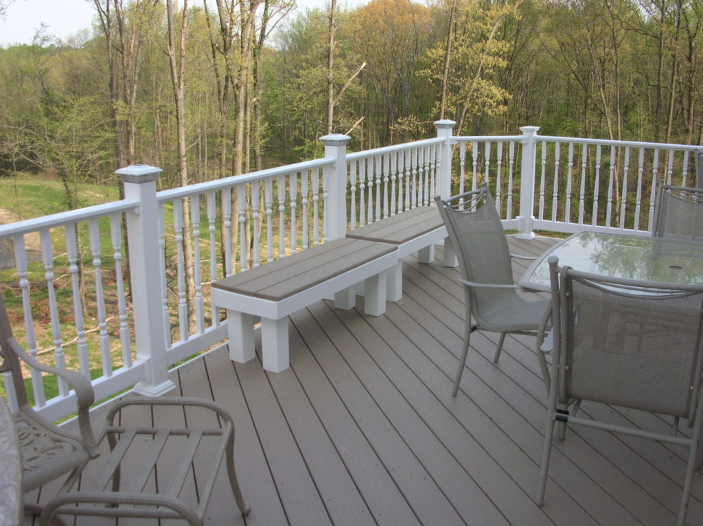 A deck with a white railing and some furniture