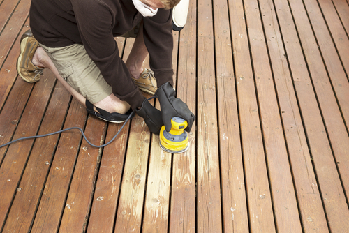 A man sanding and refinishing a deck in Maryland.
