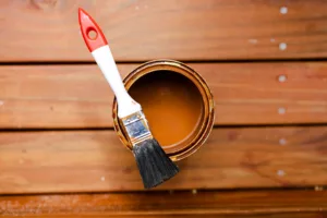 open pot of deck stain with brush